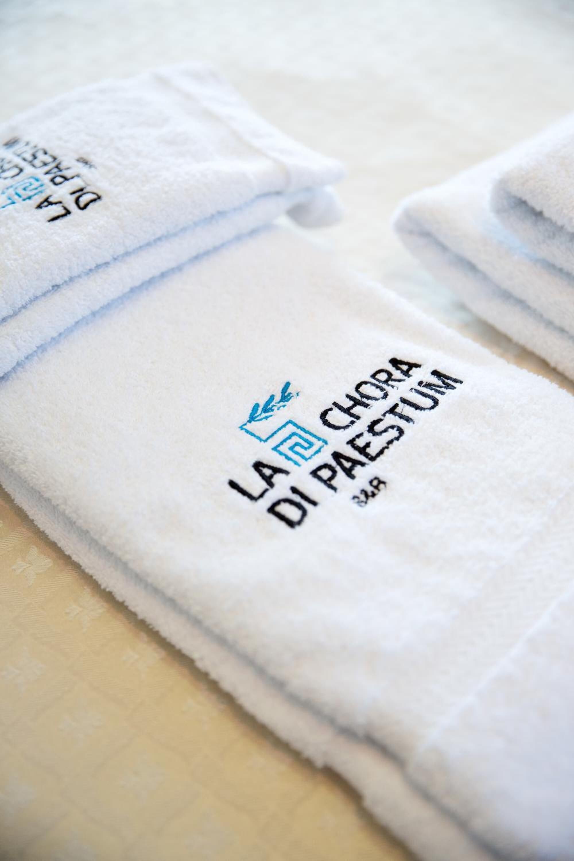 Folded white towels with embroidered text and a logo.