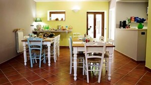 Un coin repas avec une table et des chaises en bois, un radiateur et une étagère contenant divers objets.