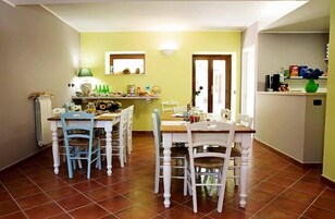 Un comedor con una mesa y sillas de madera, un radiador y una estantería con diversos objetos.