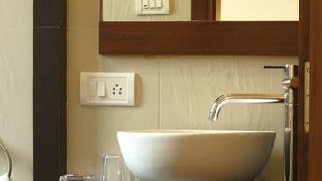 A bathroom with a white vessel sink, a mirror above it, and a black countertop.
