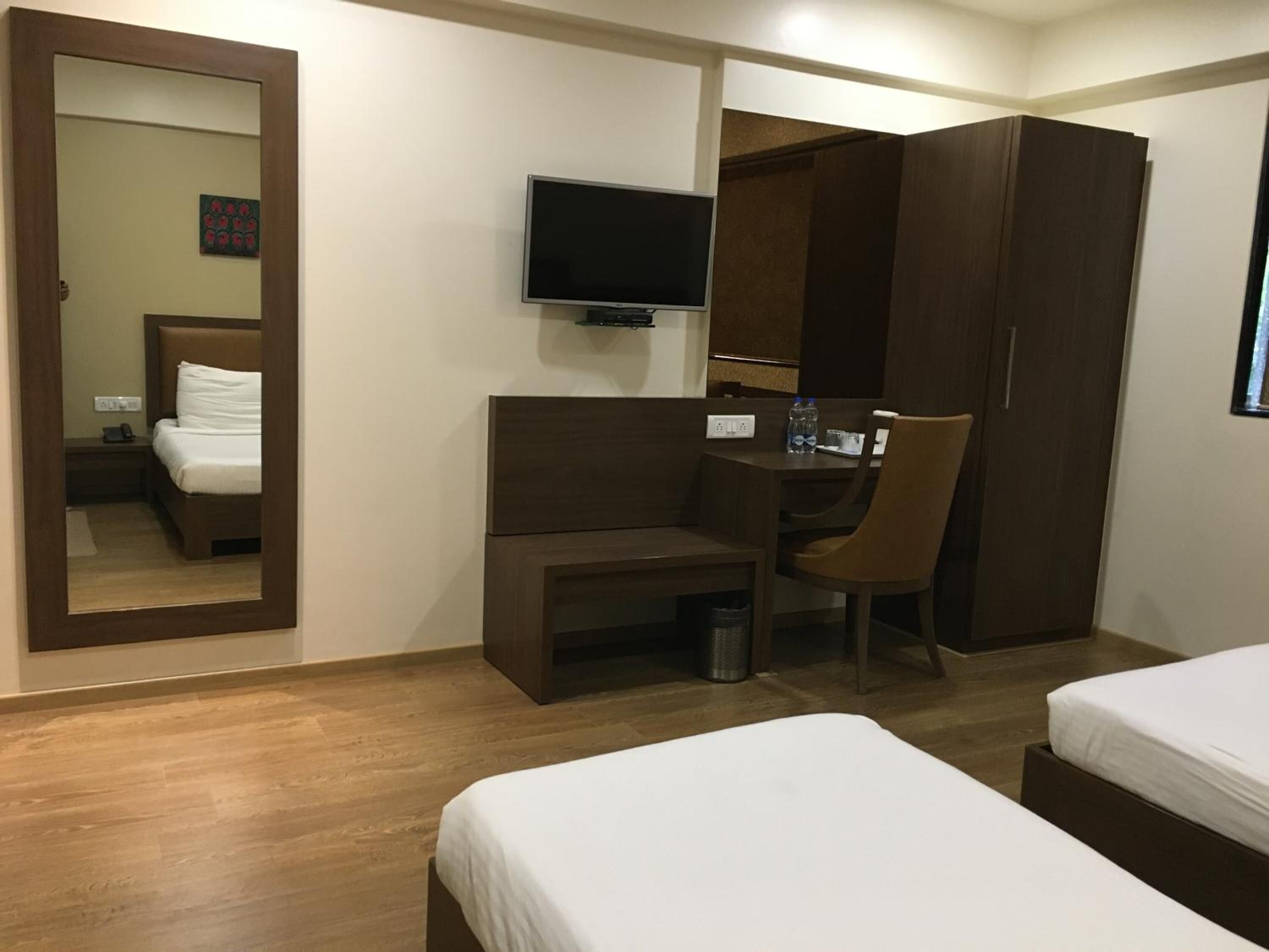 Une chambre d’hôtel comprenant un lit, un bureau avec une chaise, une télévision et une armoire.