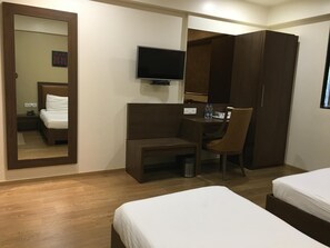 A hotel room with a bed, a desk with a chair, a television, and a wardrobe. - Hotel Amigo (Mumbai)