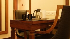 A wooden dining table with two chairs, a kettle, and a cup.
