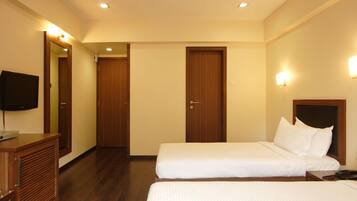 A hotel room with two single beds, a wooden dresser, a television, and a mirror.