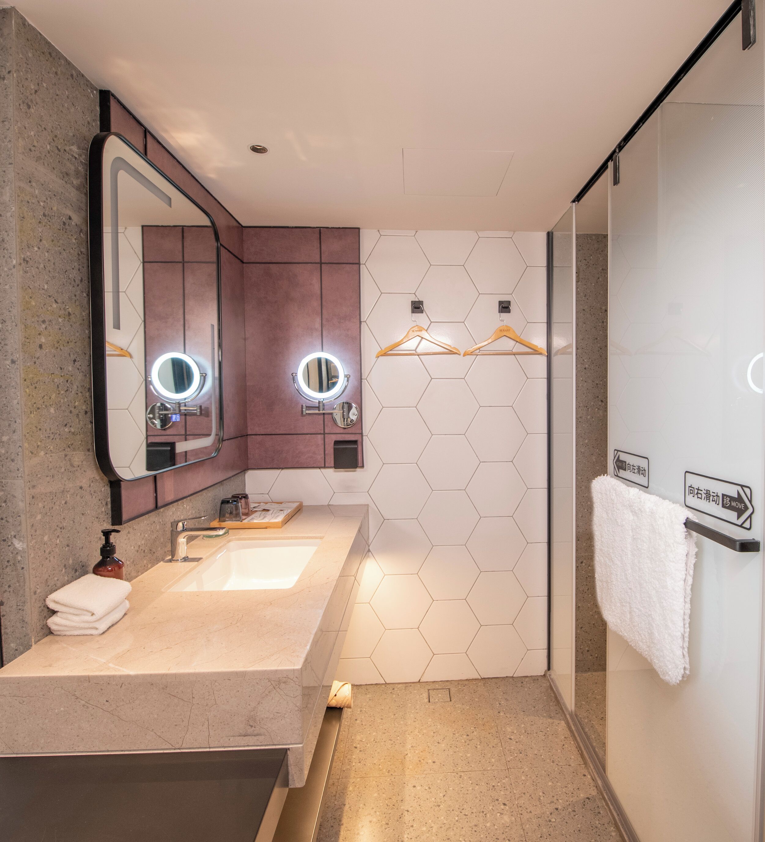 A modern bathroom with a dual sink, vanity mirror, and a towel rack.