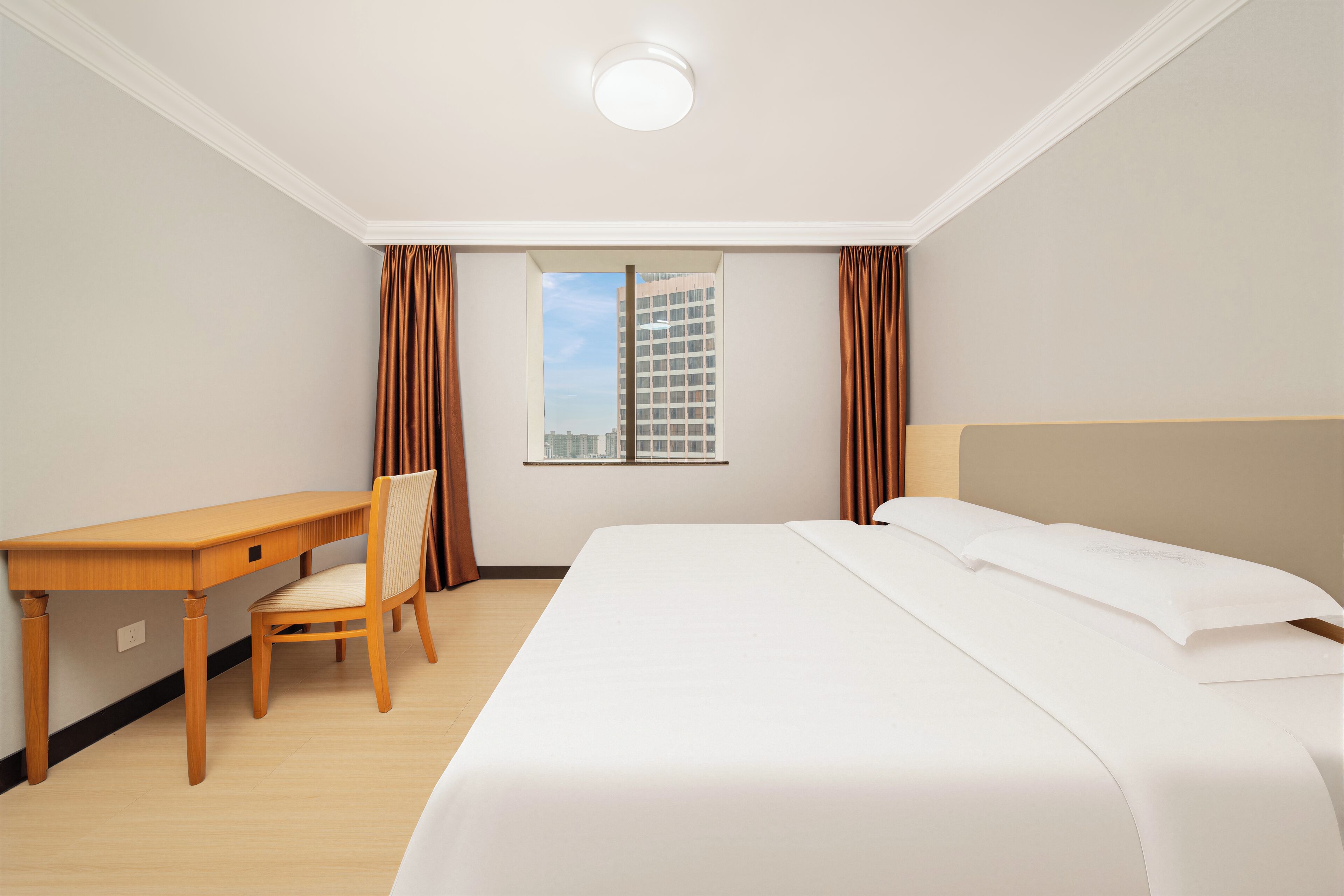A hotel room with a bed, a desk, and a chair.