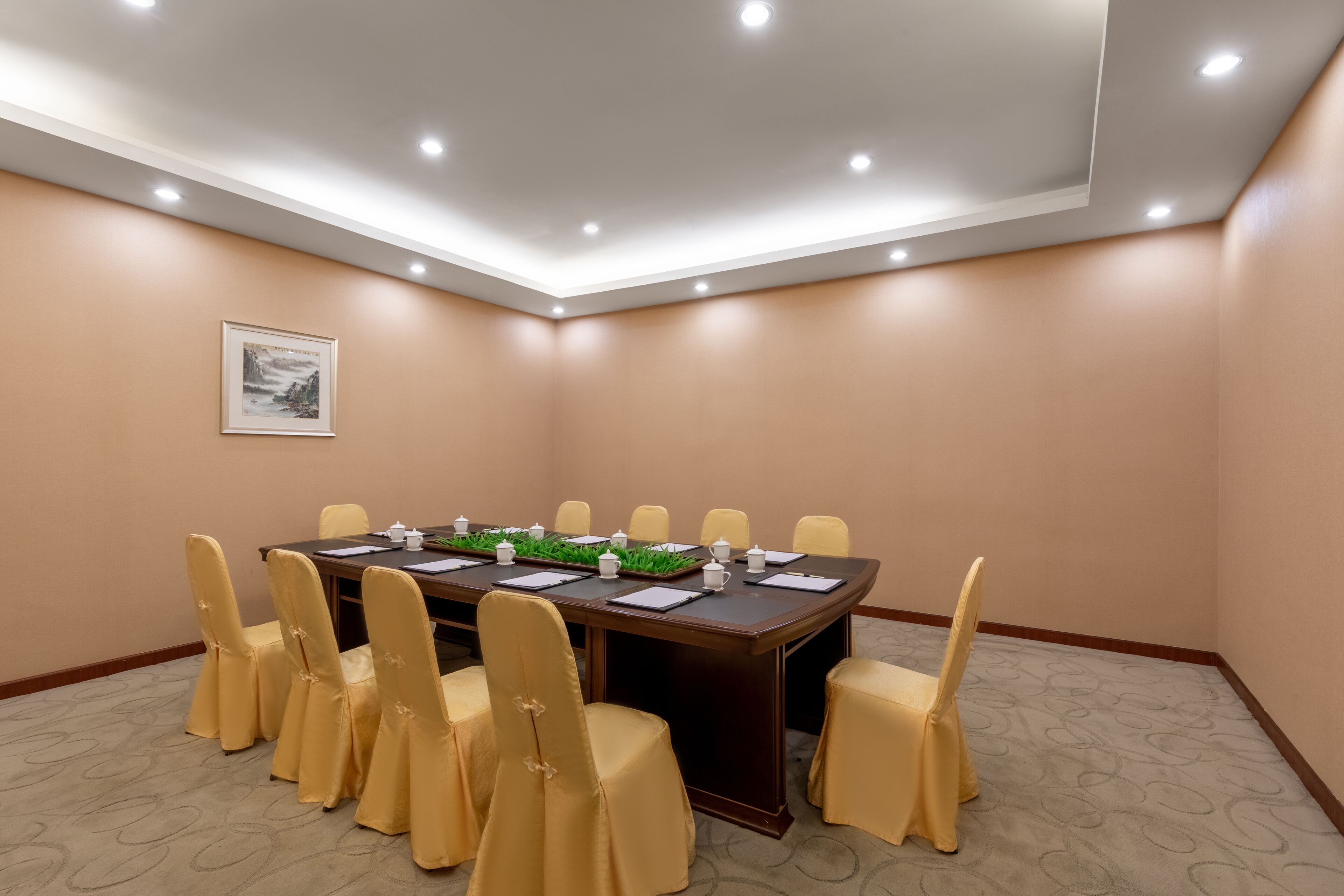 Une salle de conférence avec une longue table, des chaises et un tableau encadré accroché au mur.
