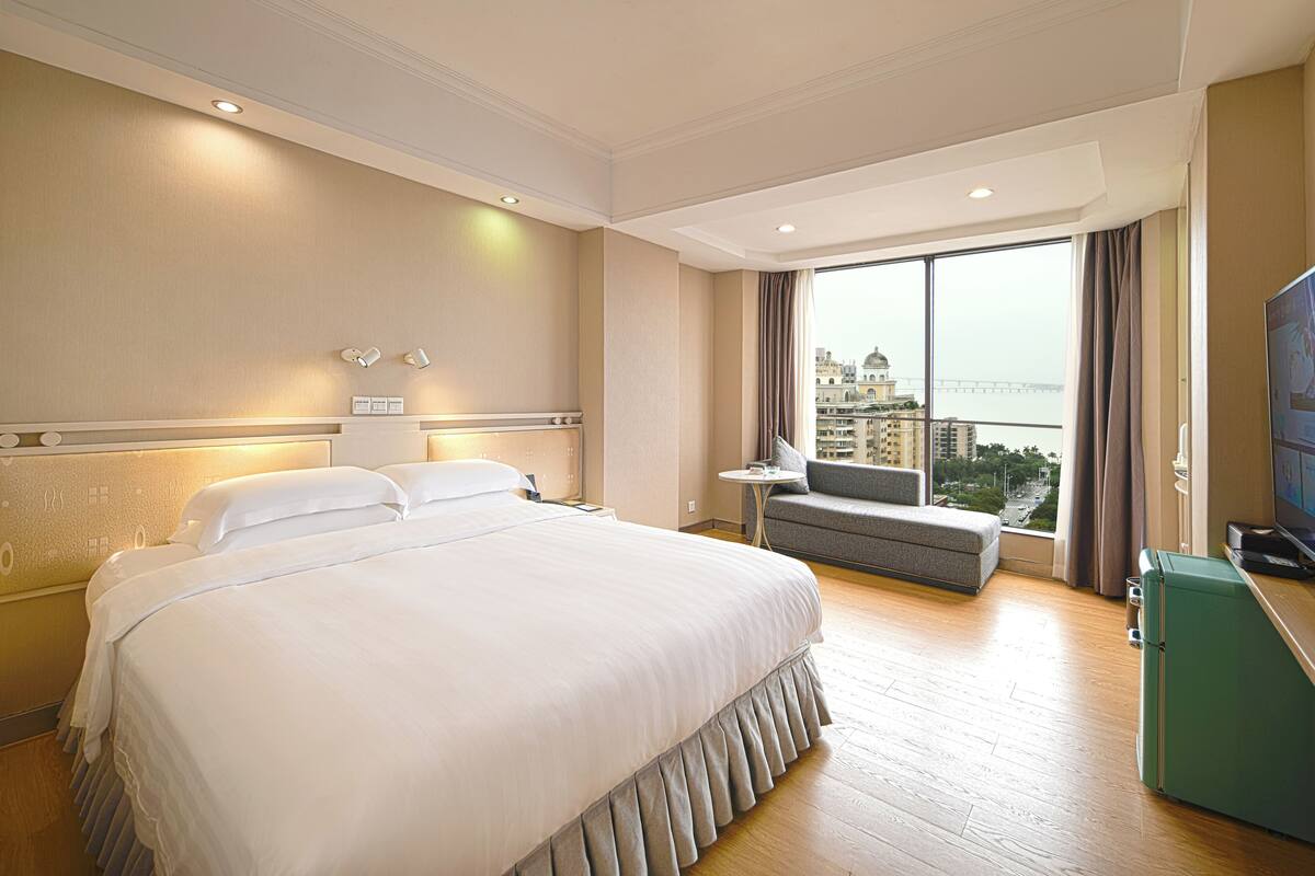 Ein Hotelzimmer mit einem großen Bett, einer Sitzecke mit Blick und einem Fernseher.