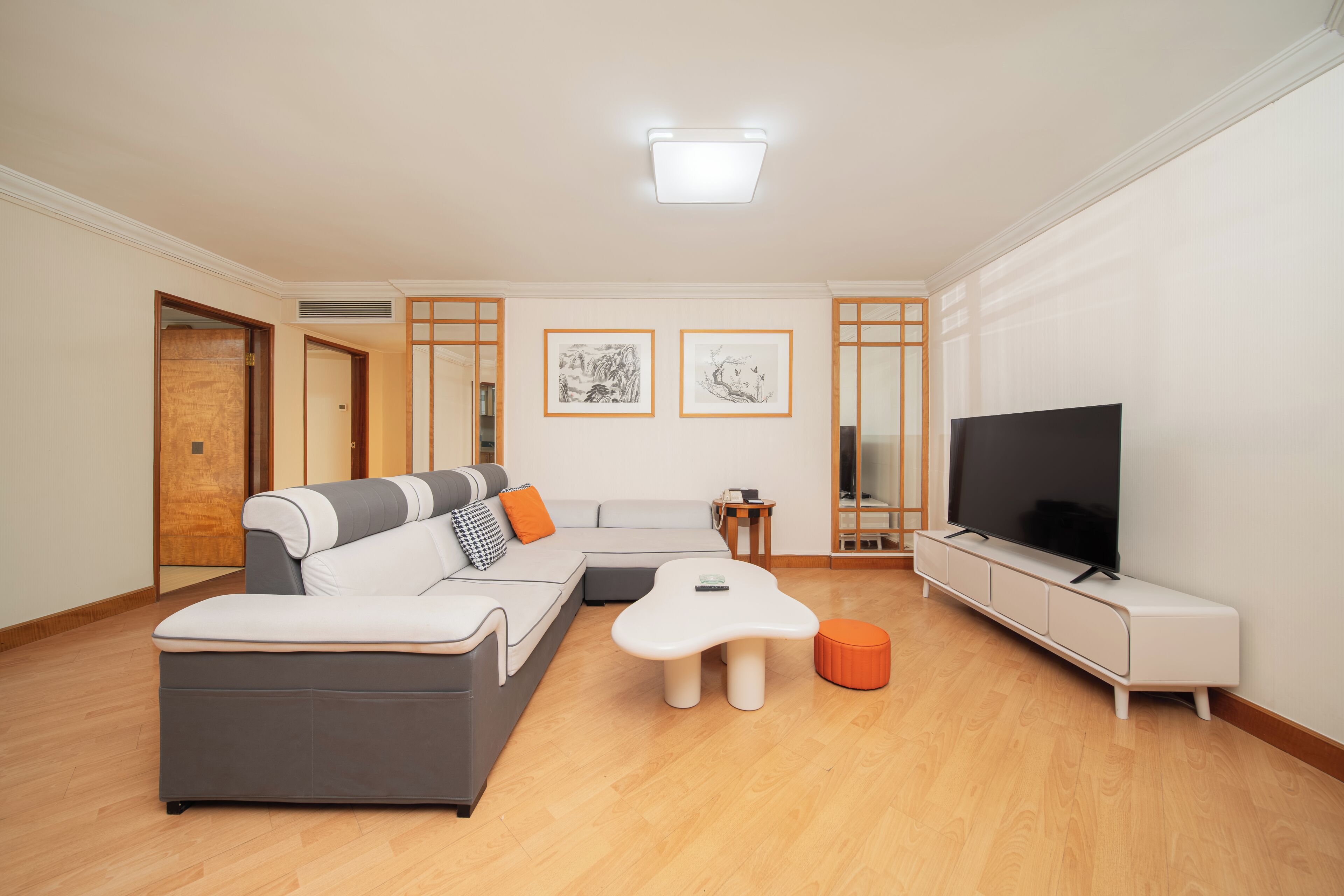 Una sala de estar moderna con un sofá modular, un televisor de pantalla plana y una mesa de centro.
