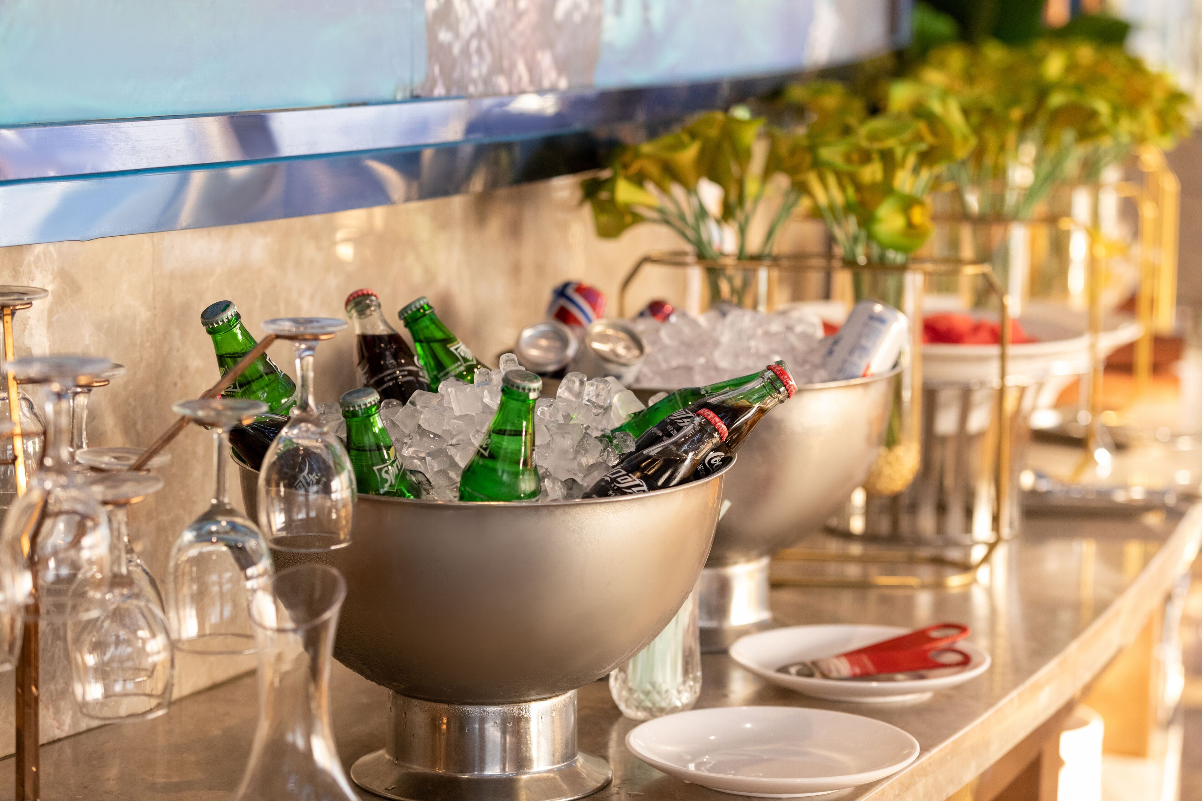 A bar area with a bar counter, glasses, bottles, and a bowl of ice.