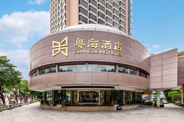 The exterior of the Guangdong Hotel with a modern design, featuring a curved facade and large windows.