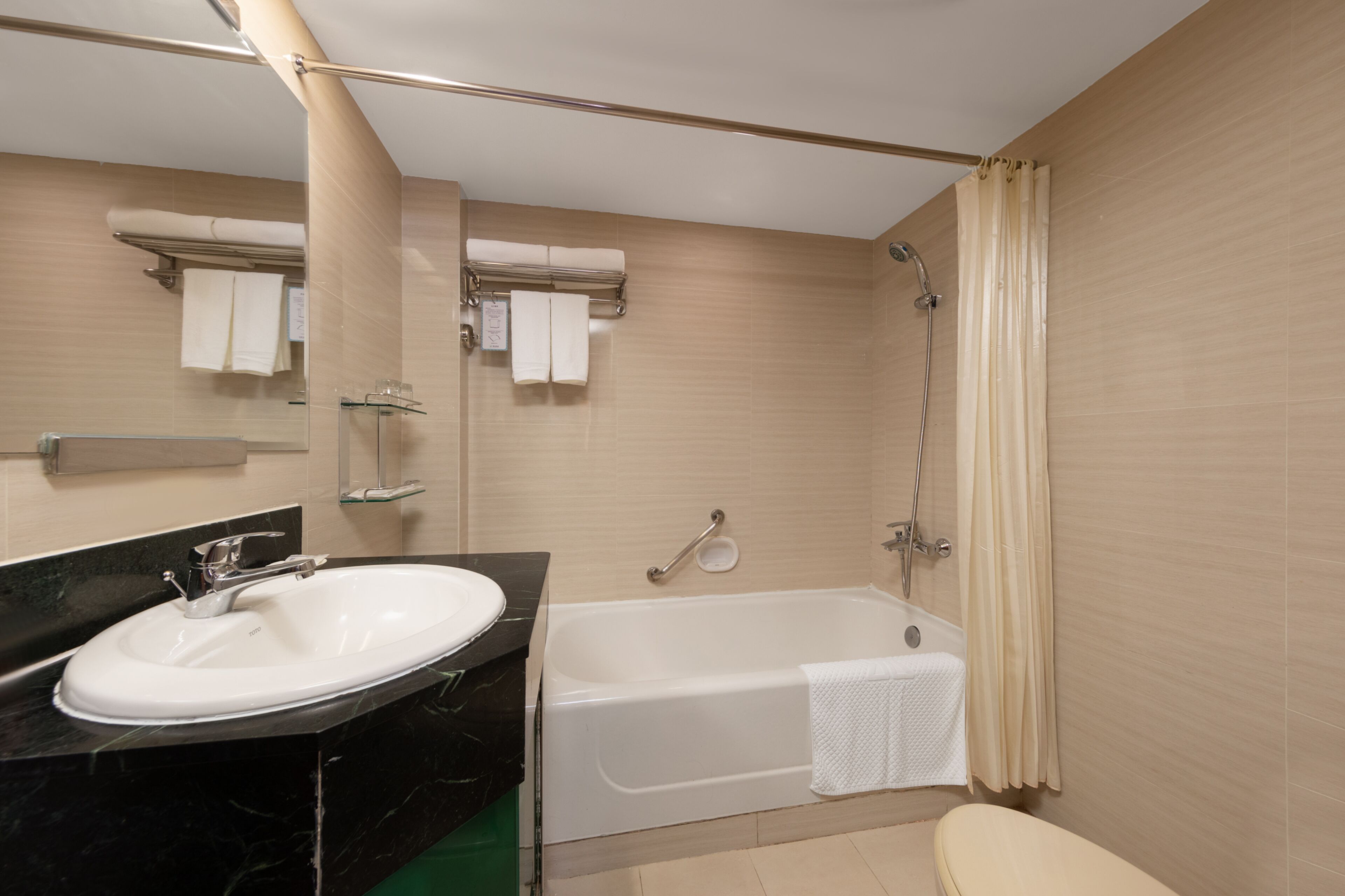 A bathroom with a sink, mirror, bathtub, and shower curtain.