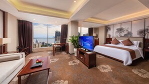 A hotel room with a large bed, a desk, a TV, and a view of the cityscape. - Guangdong Hotel Zhuhai (Zhuhai)