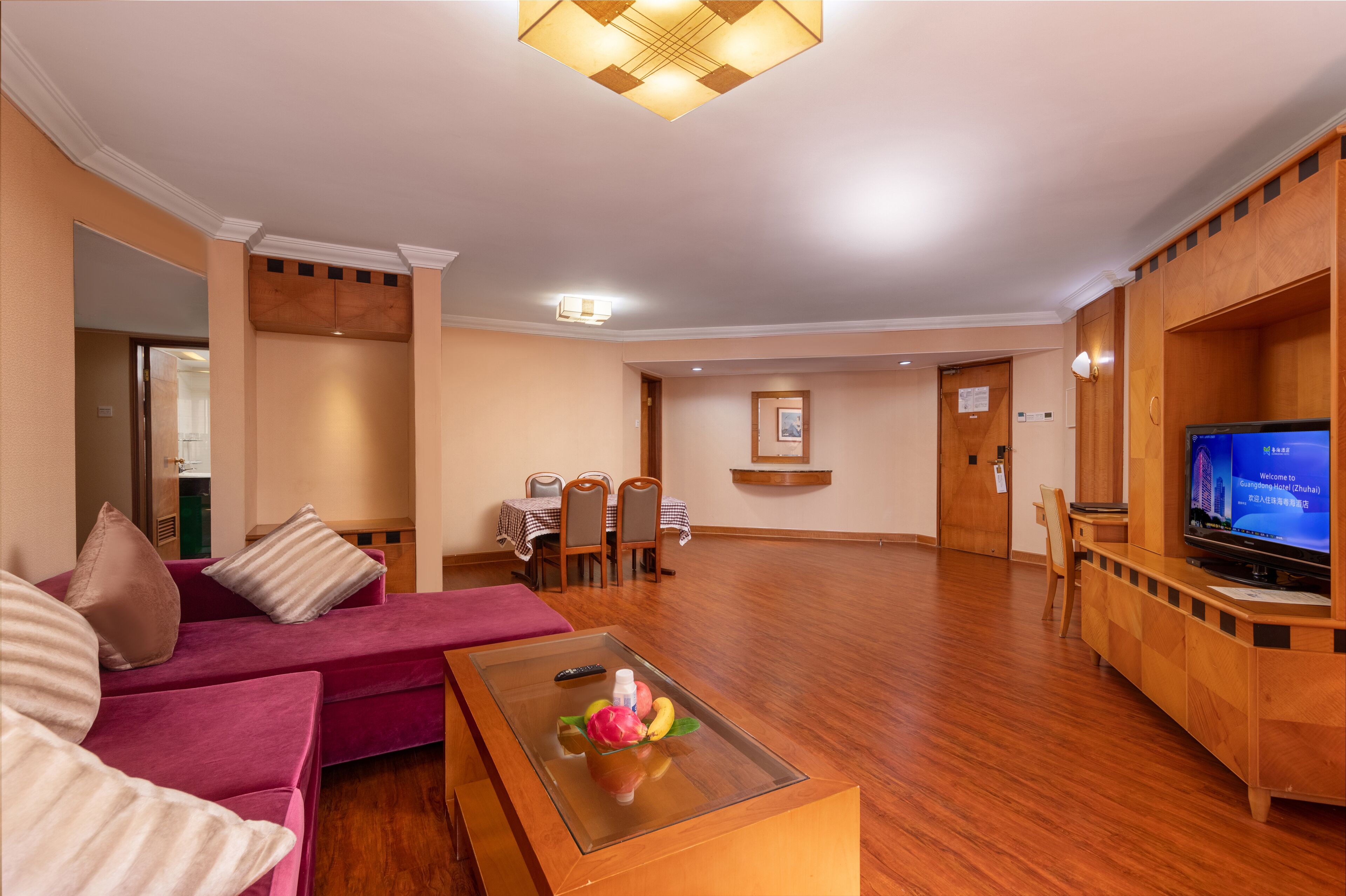A spacious living room with a red sofa, a glass coffee table, and a wooden TV stand.