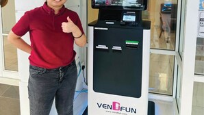 Eine Person steht neben einem Automaten mit digitaler Anzeige, einem Schild für 'HAVONA HOTEL' und dem 'VENDFUN'-Logo.