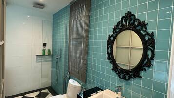 Un baño con piso a cuadros blanco y negro, un inodoro blanco, un lavamanos y un espejo con marco decorativo.