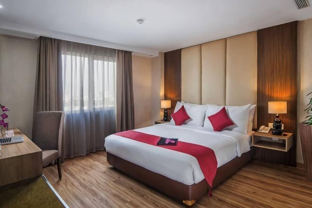 A hotel room with a large bed, bedside tables, a desk, and a chair.