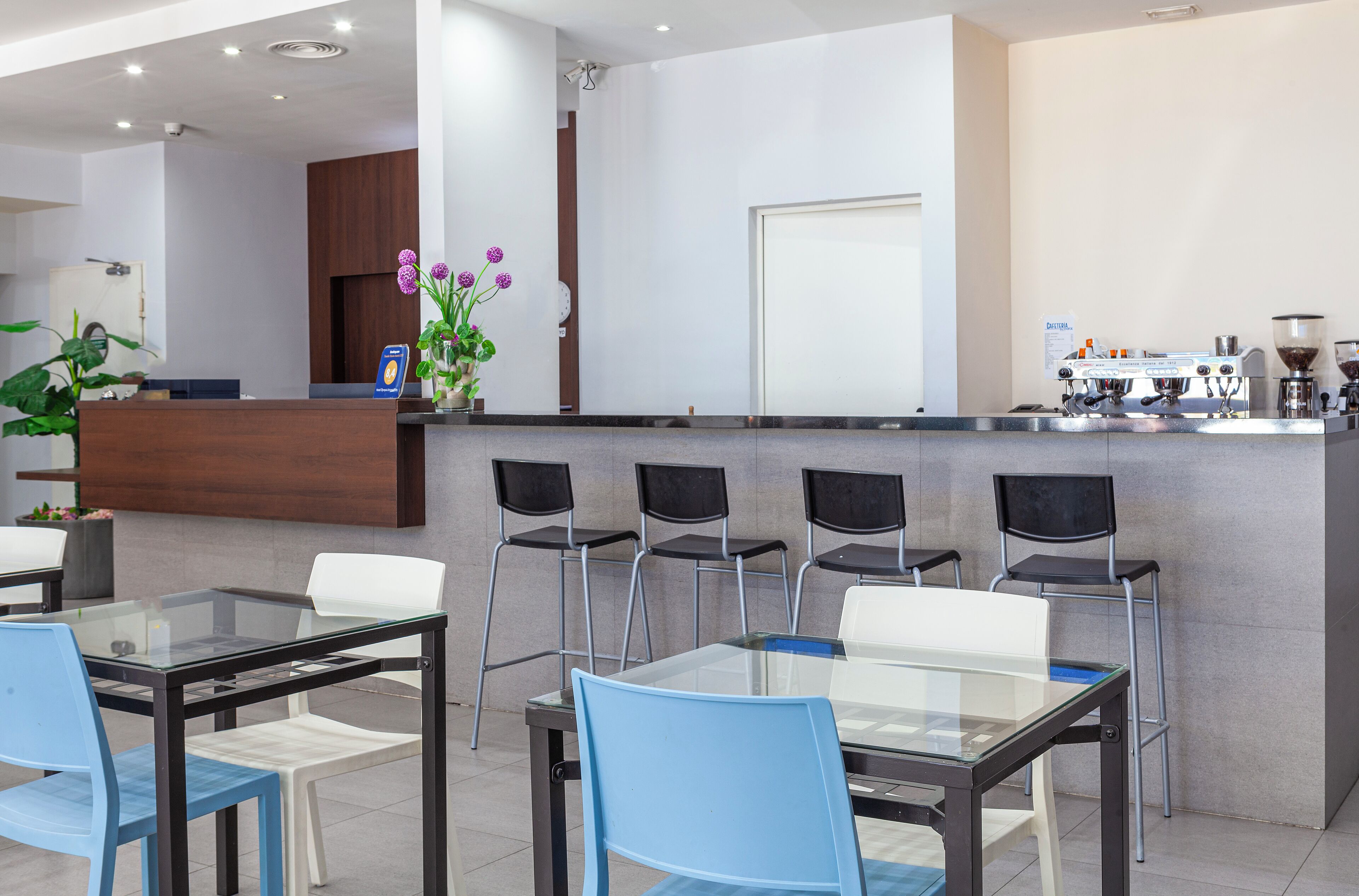 Un café moderno con una recepción, zona de estar y máquinas de café.