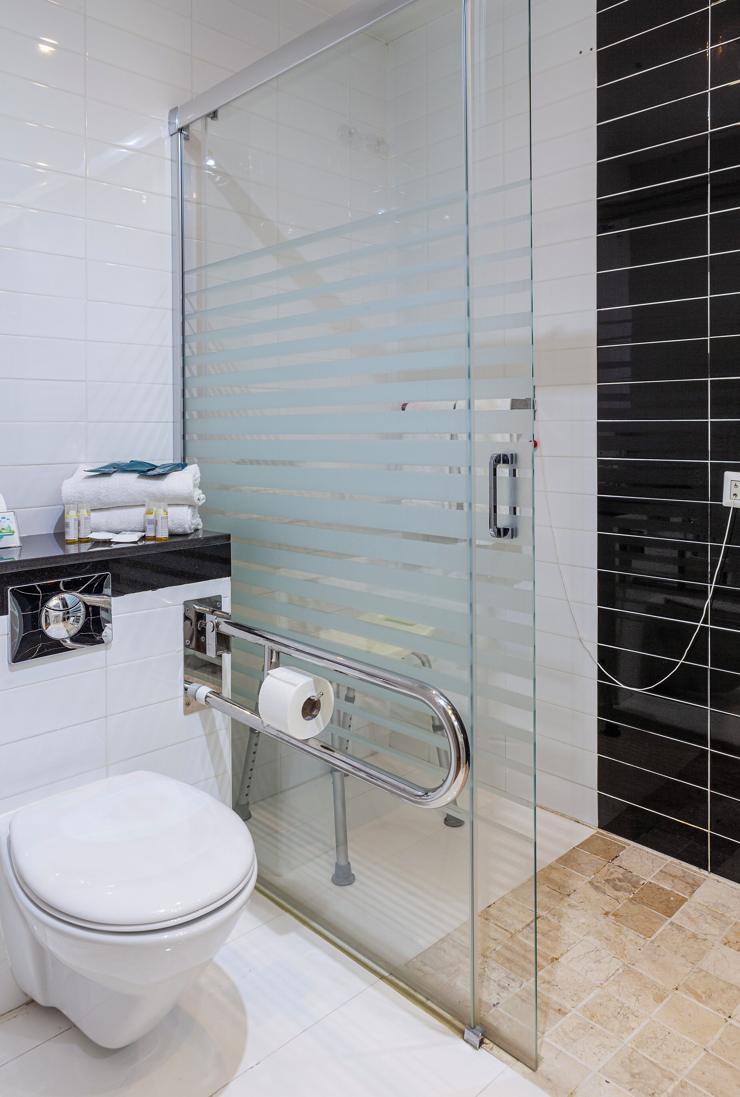 A modern bathroom with a glass shower enclosure, a toilet, and a sink with toiletries.