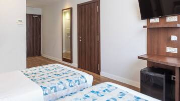 A hotel room with two beds, a TV, a small fridge, and a mirror.