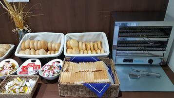 Una mesa de buffet con panes, pasteles y salsas diversas.