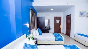 A hotel room with two beds, a desk with a mirror, and a small kitchenette.