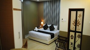 Une chambre d’hôtel comprenant un lit, une table de chevet, une lampe et une armoire.