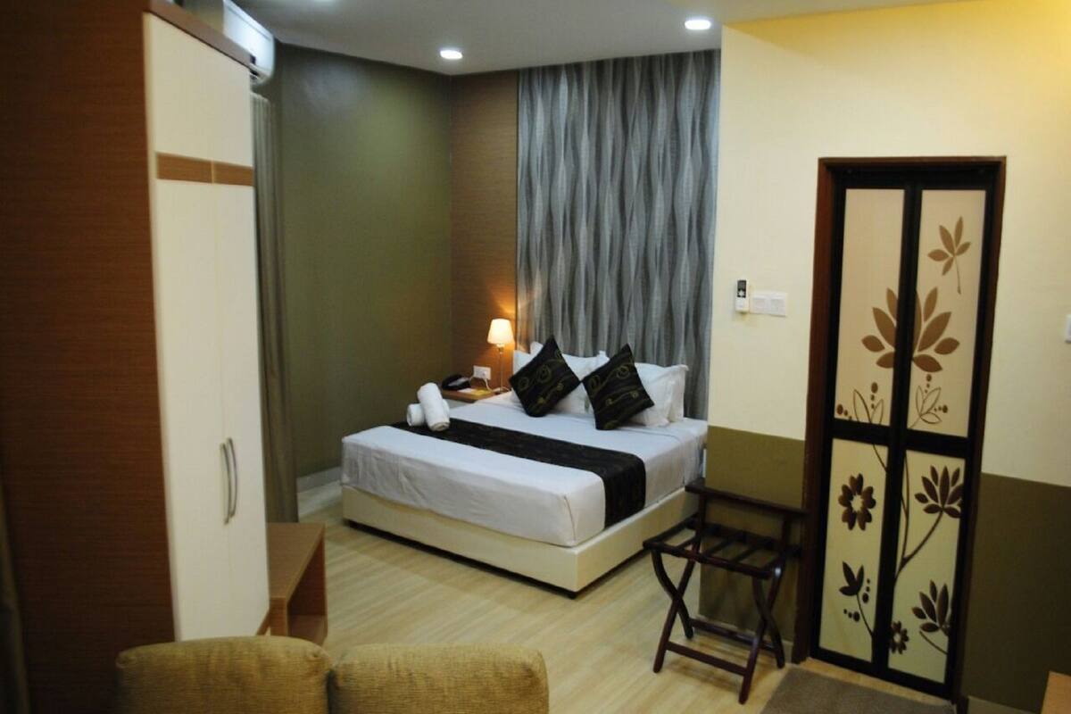 Una habitación de hotel con cama, mesita de noche, lámpara y armario.
