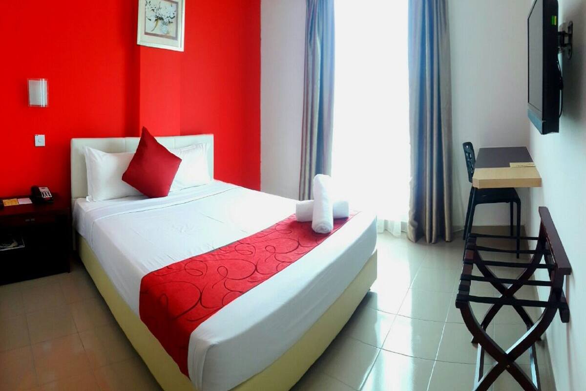 Una habitación de hotel con una cama, un escritorio y una silla.