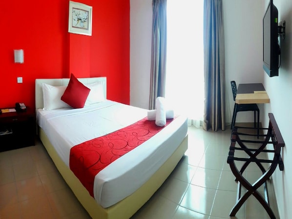 Una habitación de hotel con una cama, un escritorio y una silla.