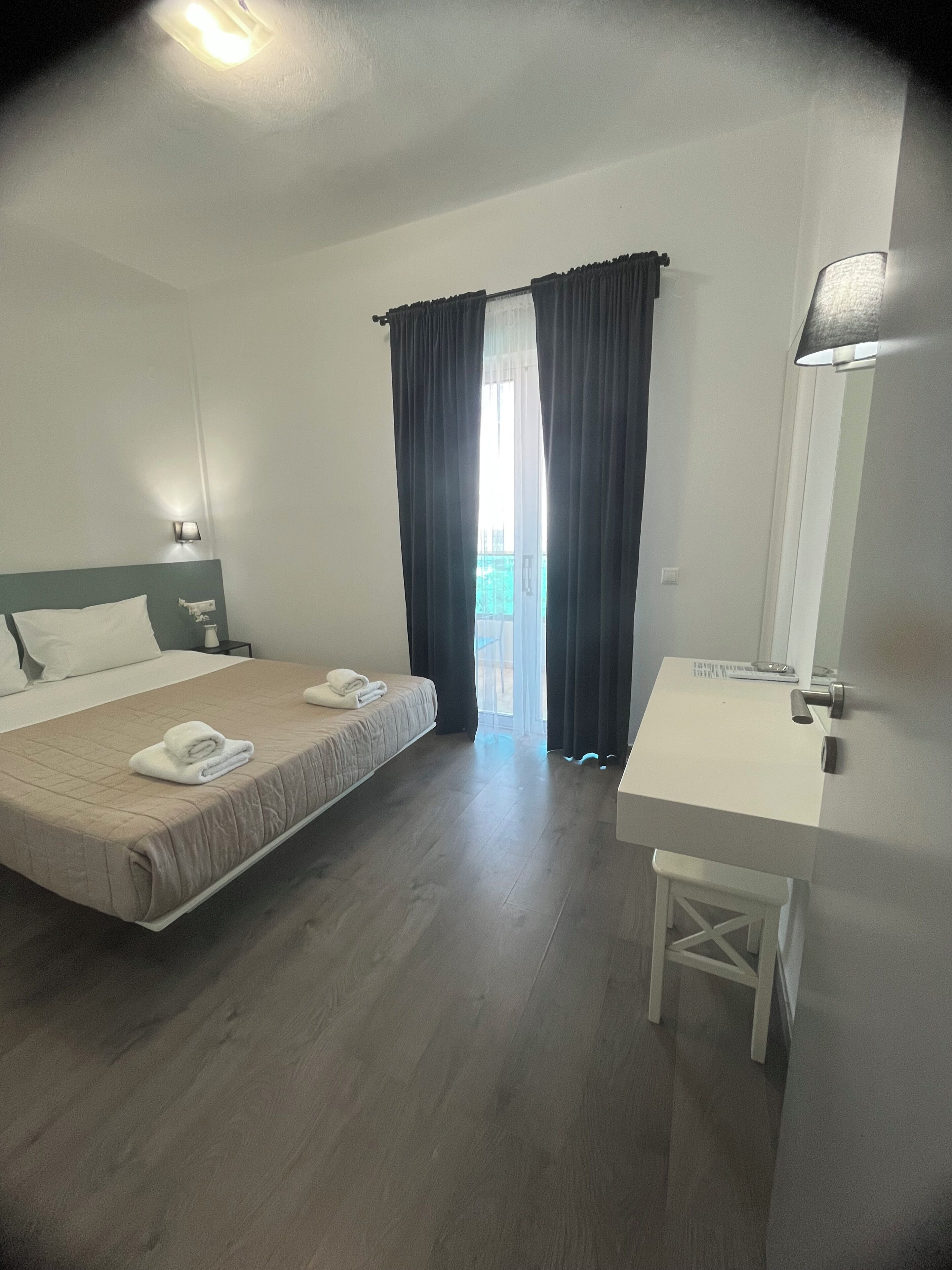Une chambre d’hôtel comprenant un lit, une table de chevet, une salle de bain avec un lavabo et une vue sur l’extérieur.