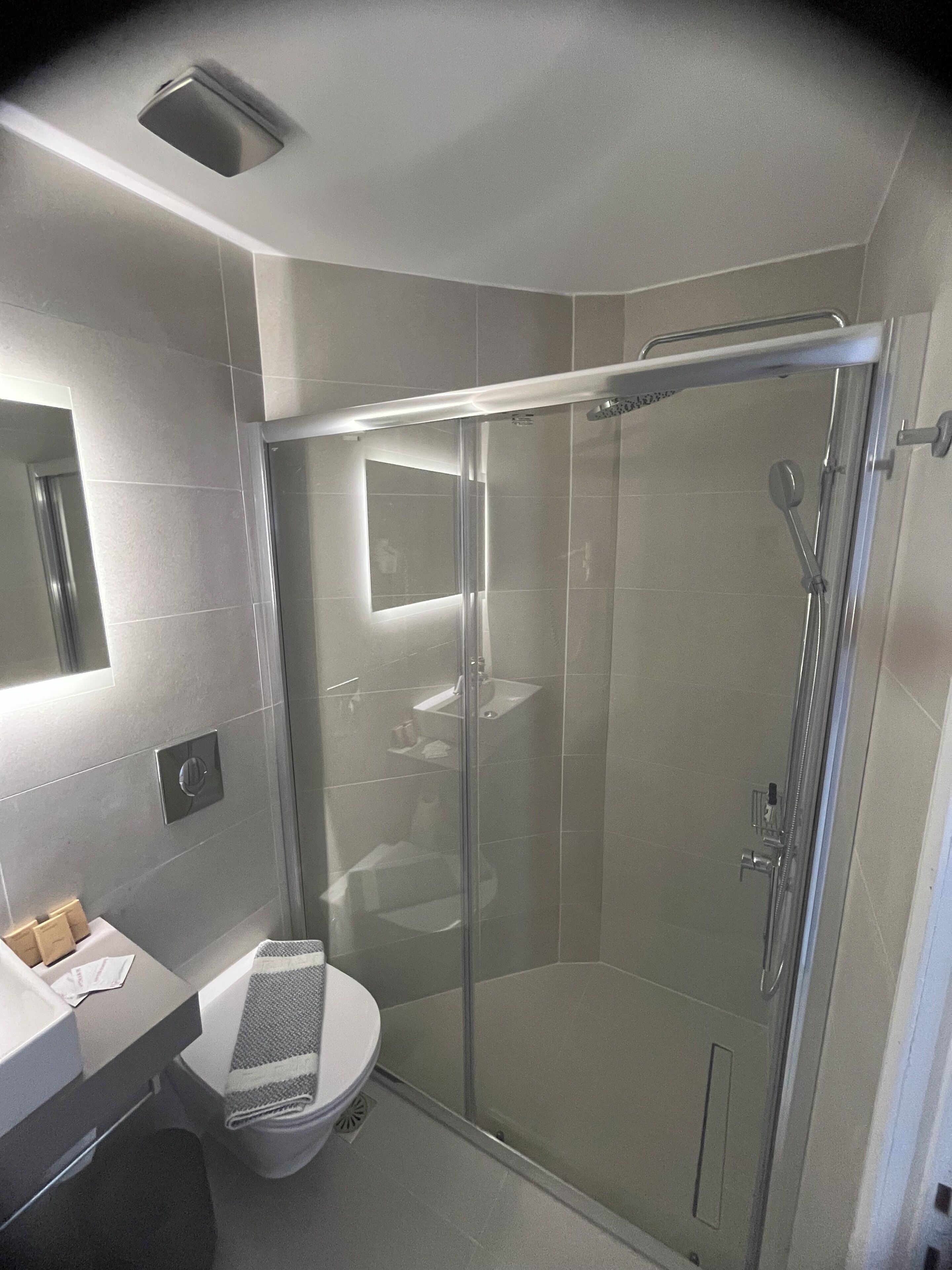 A modern bathroom with a glass-enclosed shower, a toilet, and a sink.