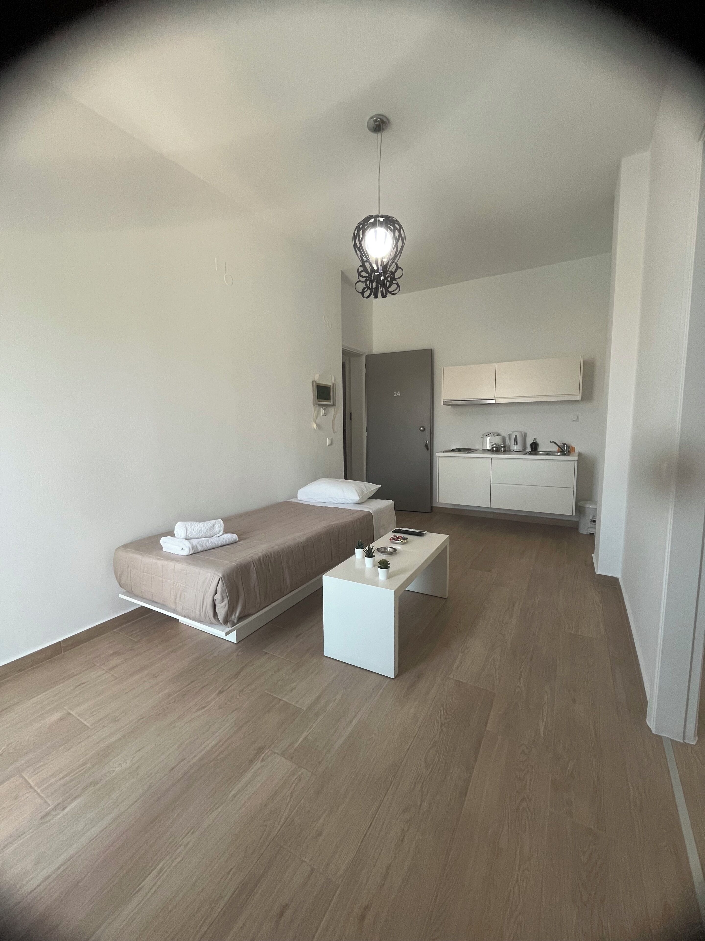 Ein modernes, minimalistisches Schlafzimmer mit einem Einzelbett, einem Nachttisch und einem kleinen Schreibtisch.