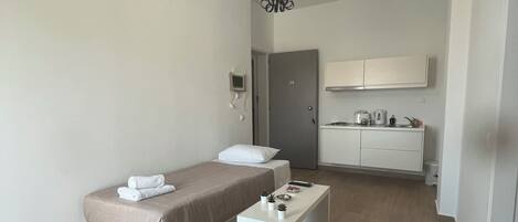 Ein modernes, minimalistisches Schlafzimmer mit einem Einzelbett, einem Nachttisch und einem kleinen Schreibtisch.
