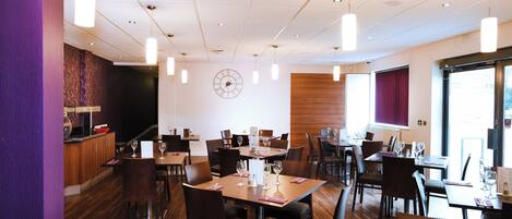 Un restaurante con varias mesas, sillas e iluminación colgante.