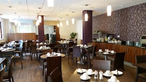 A restaurant with multiple dining tables and chairs, a counter with a menu, and a patterned wall. - Lancaster Hotel (Uxbridge)
