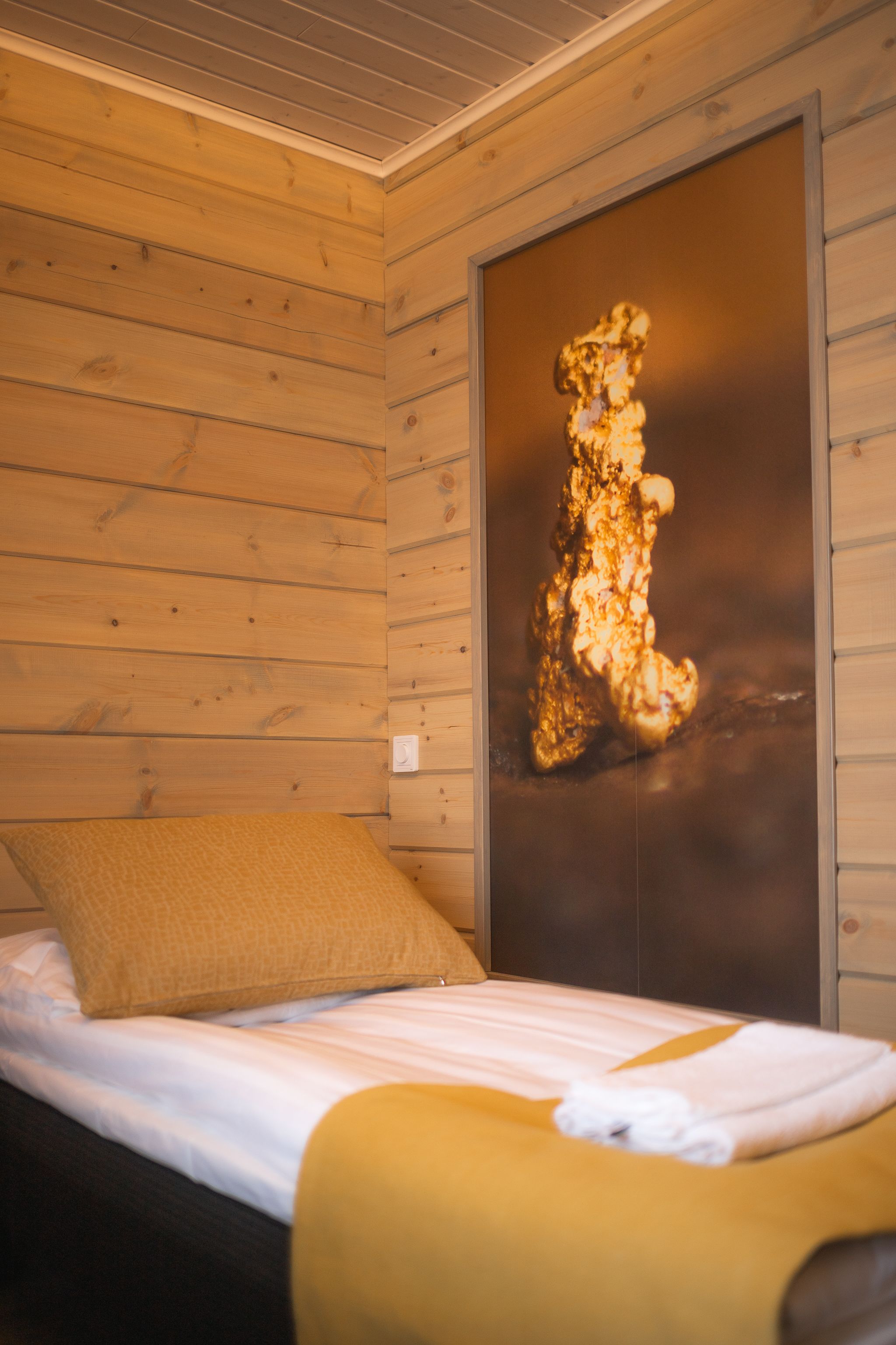 Una habitación de cabaña de madera con una cama, una obra de arte enmarcada y un techo de madera.