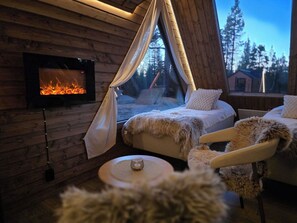A cozy cabin interior with a fireplace, a bed, and a chair.