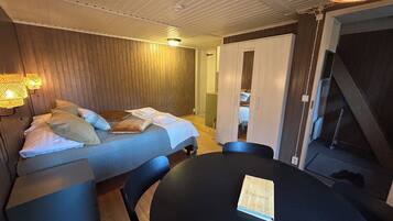 A room with a bed, a table, and a chair. There is a book on the table.