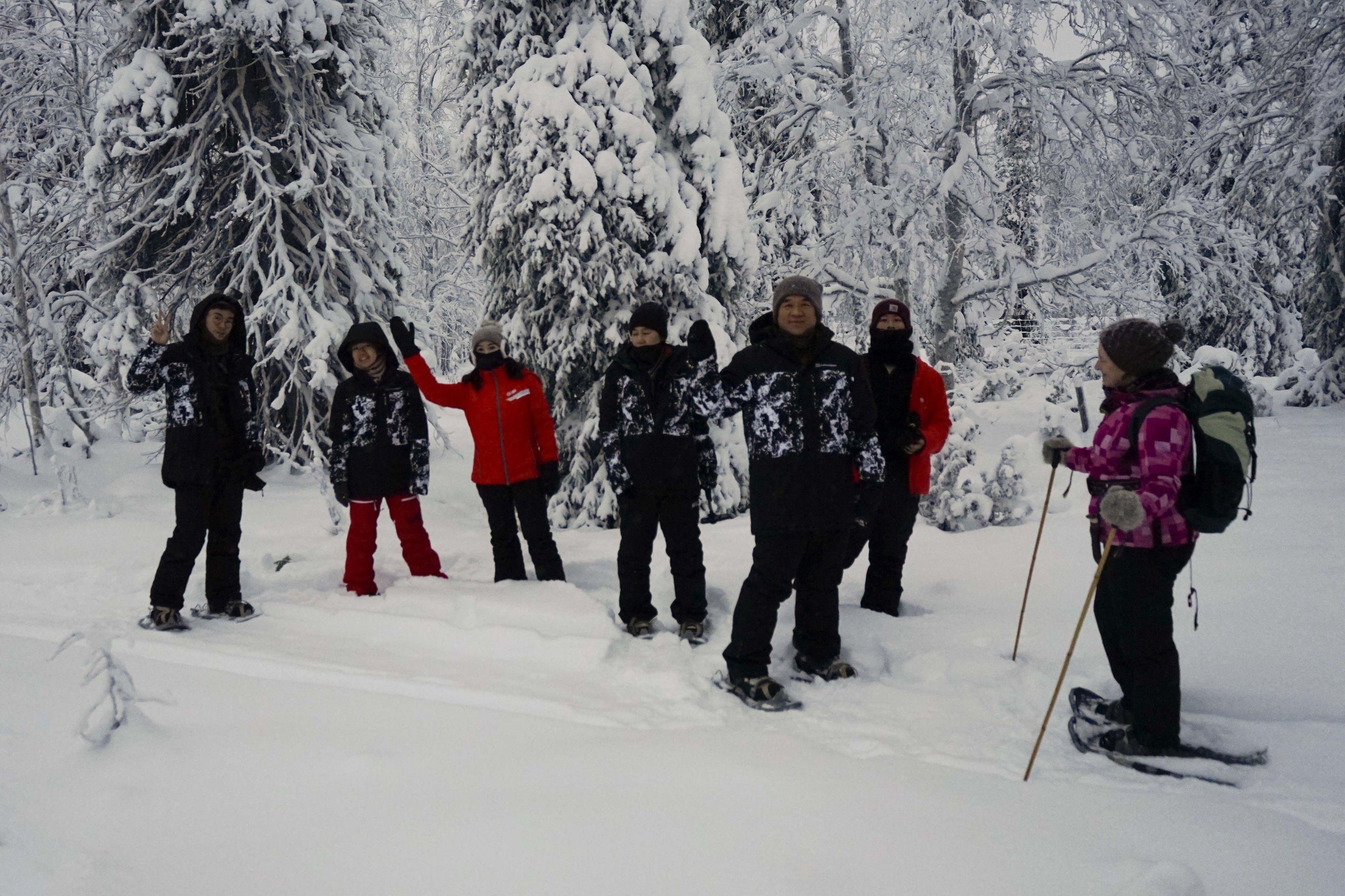 A group of people in winter clothing standing in a snowy forest.