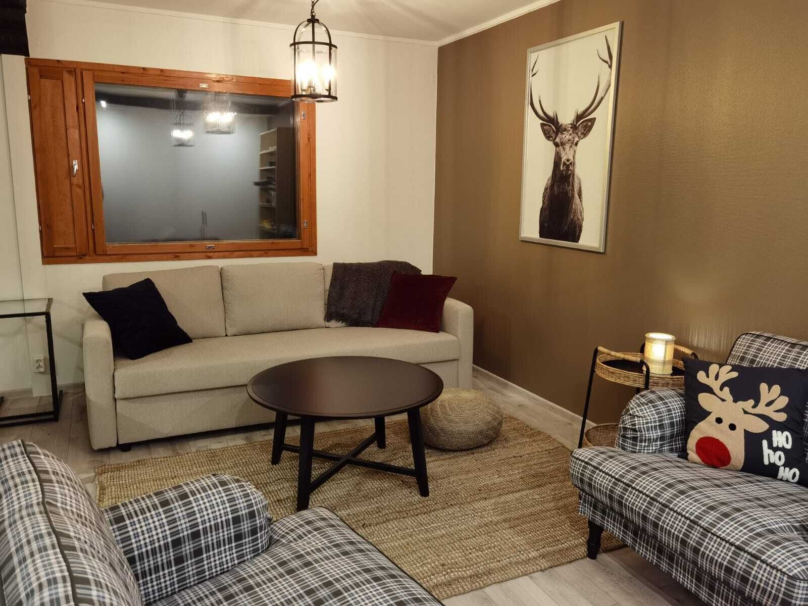 Una sala de estar acogedora con un sofá, una mesa de centro redonda y una alfombra estampada.