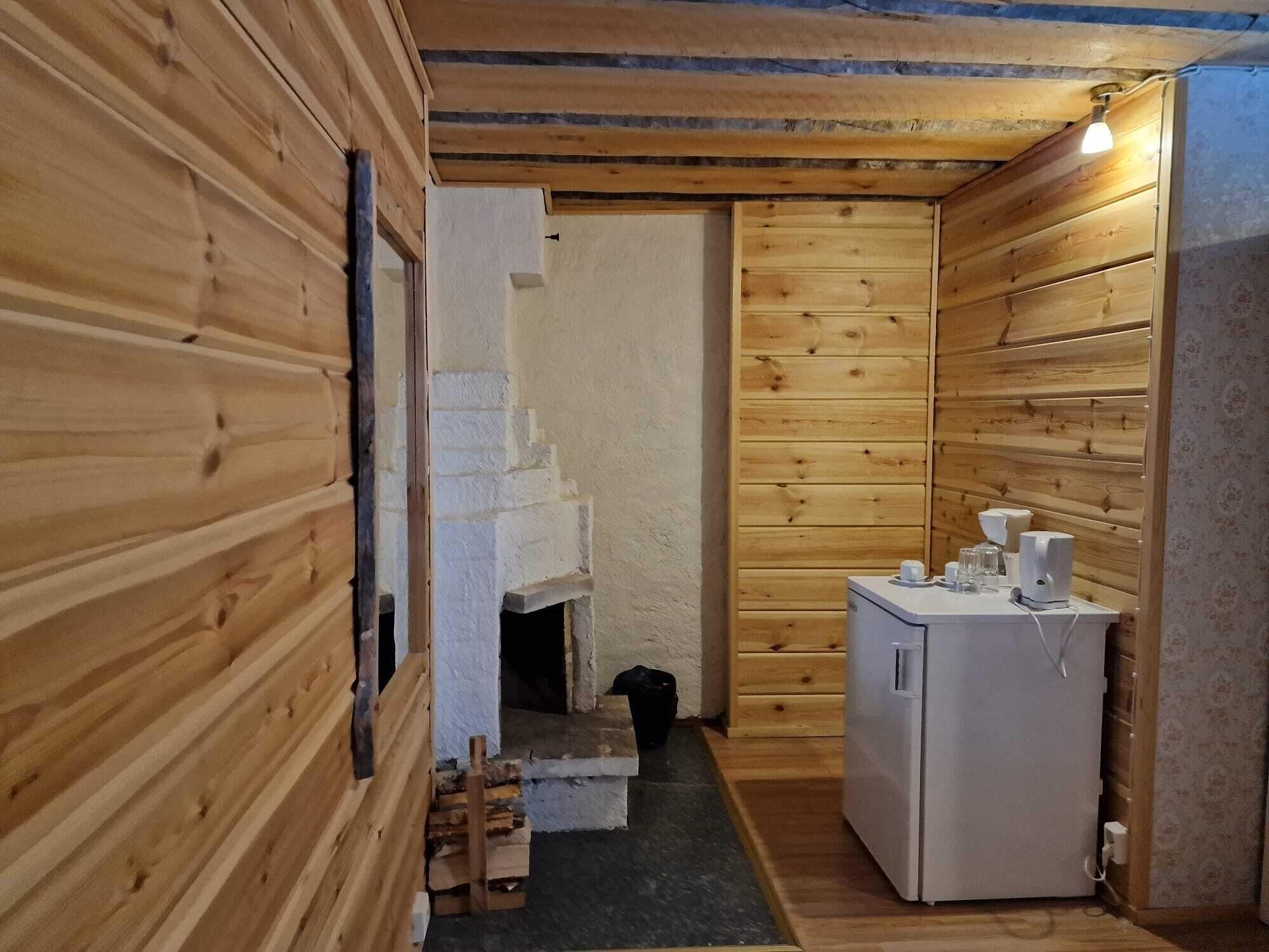 A compact wooden cabin with a small kitchenette, a built-in fireplace, and a refrigerator.
