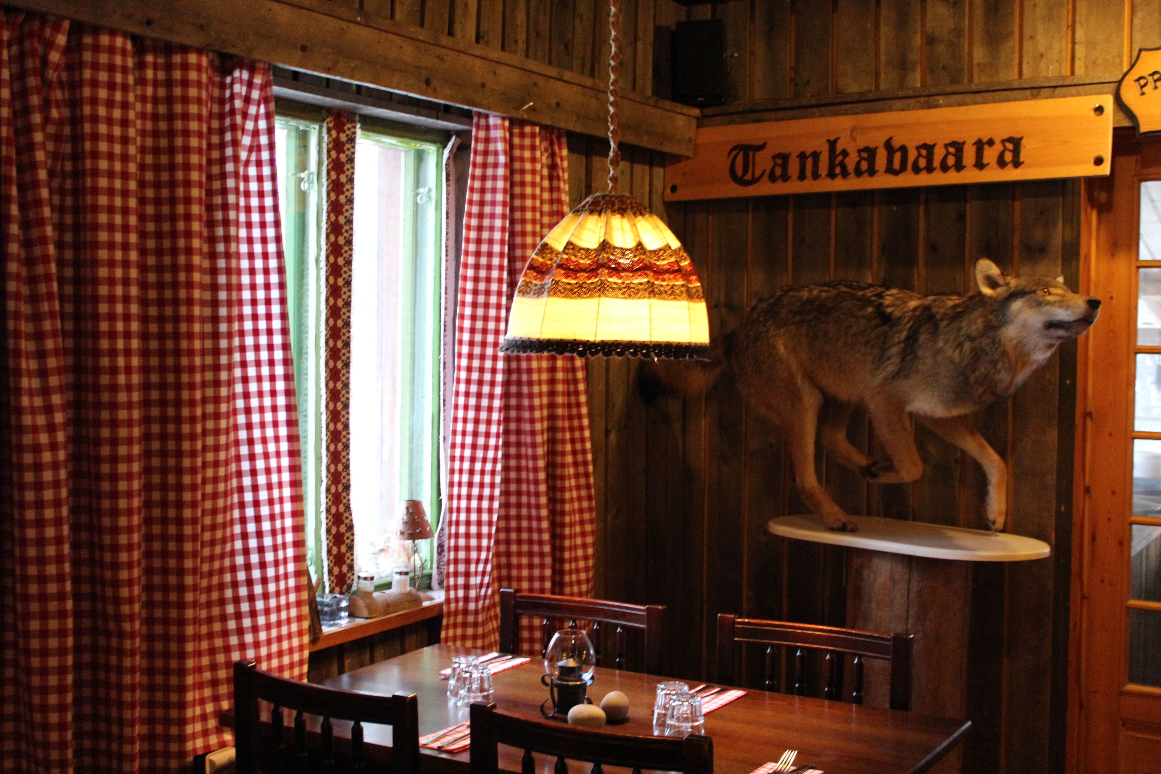 Un interior de madera con una mesa dispuesta para comer, una lámpara colgante y una cabeza de animal montada en la pared.