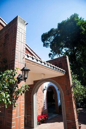 A brick building with a covered entrance, a lantern, and potted plants. - Wulai Town House (New Taipei City)