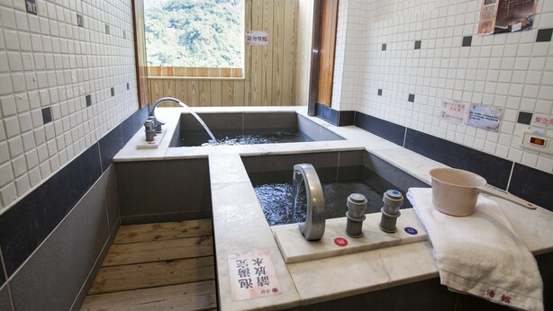Un onsen japonais traditionnel, avec un sol en bois, un lavabo et un bain à remous.
