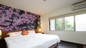 Une chambre d’hôtel avec un grand lit, une fenêtre et une fresque murale représentant des fleurs roses.
