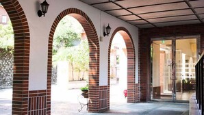 Un espace extérieur abrité, doté d’arches en briques et d’une entrée avec une porte en verre.