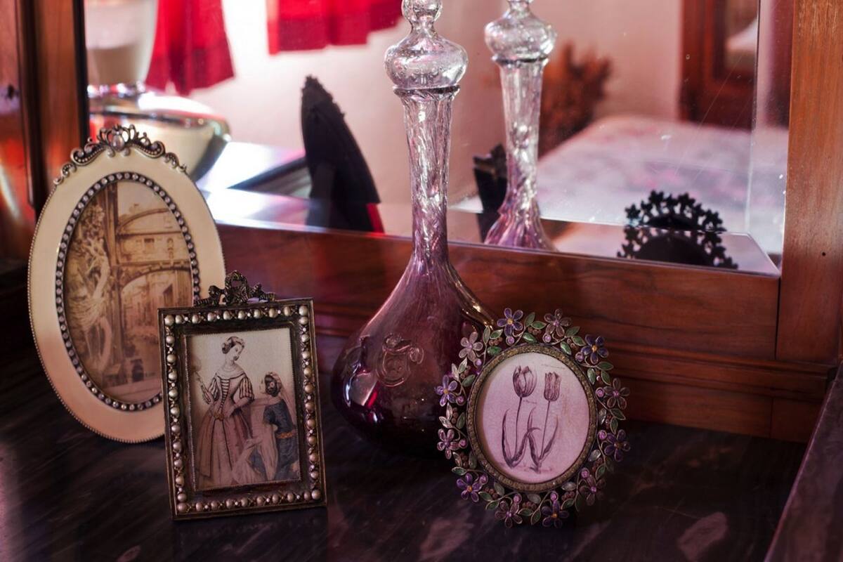 A wooden table with three decorative items: a framed picture, a vase with a floral design, and a vase with a clear glass top.