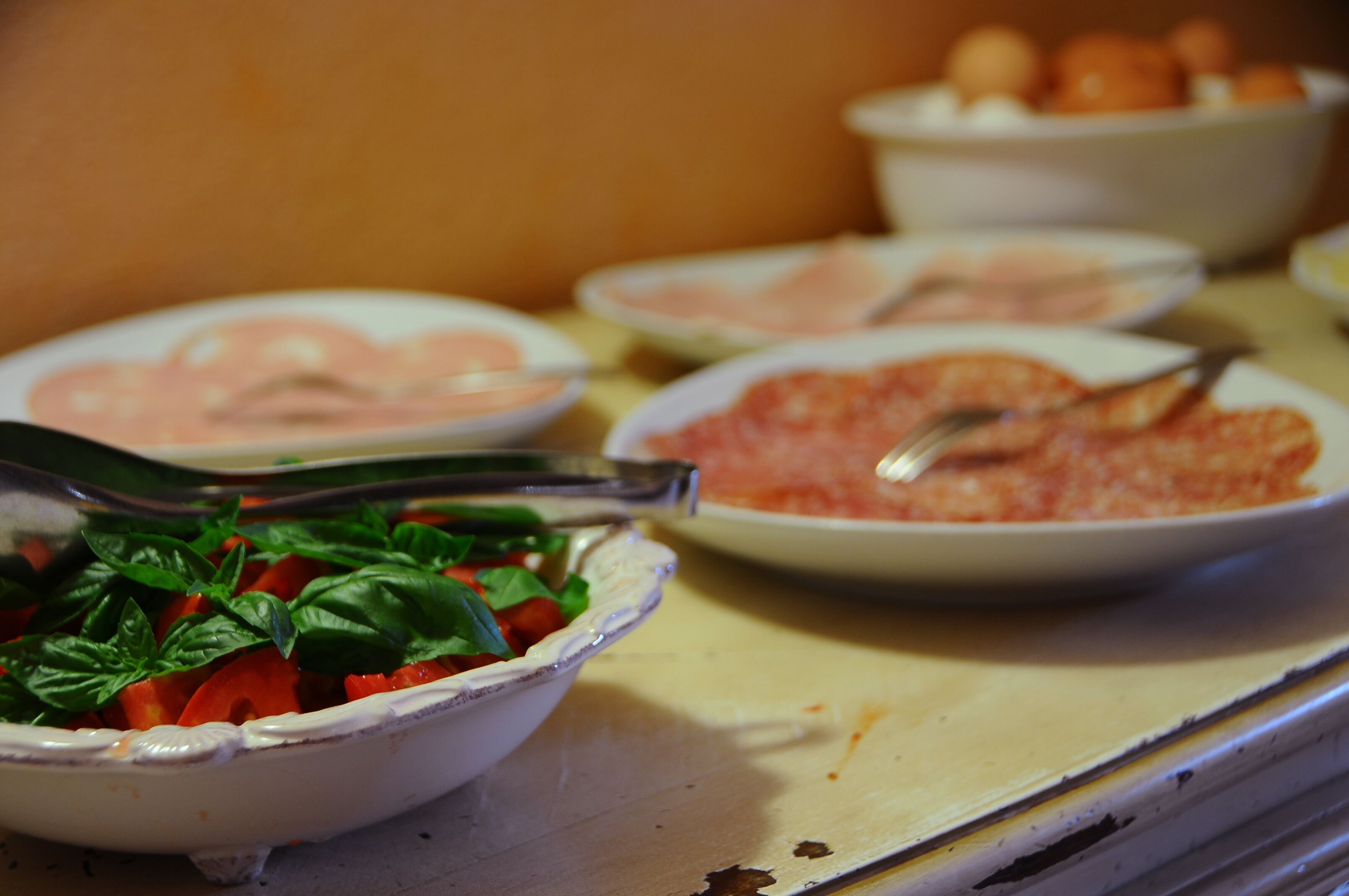 Una mesa de buffet con diversos platos, incluyendo un tazón de ensalada, un plato de carne en rodajas y un tazón de pasta.