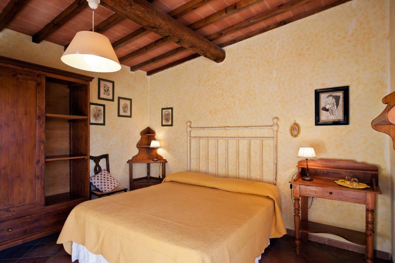 Une chambre confortable avec un lit en bois, une table de chevet avec une lampe, une armoire en bois et des tableaux encadrés accrochés au mur.